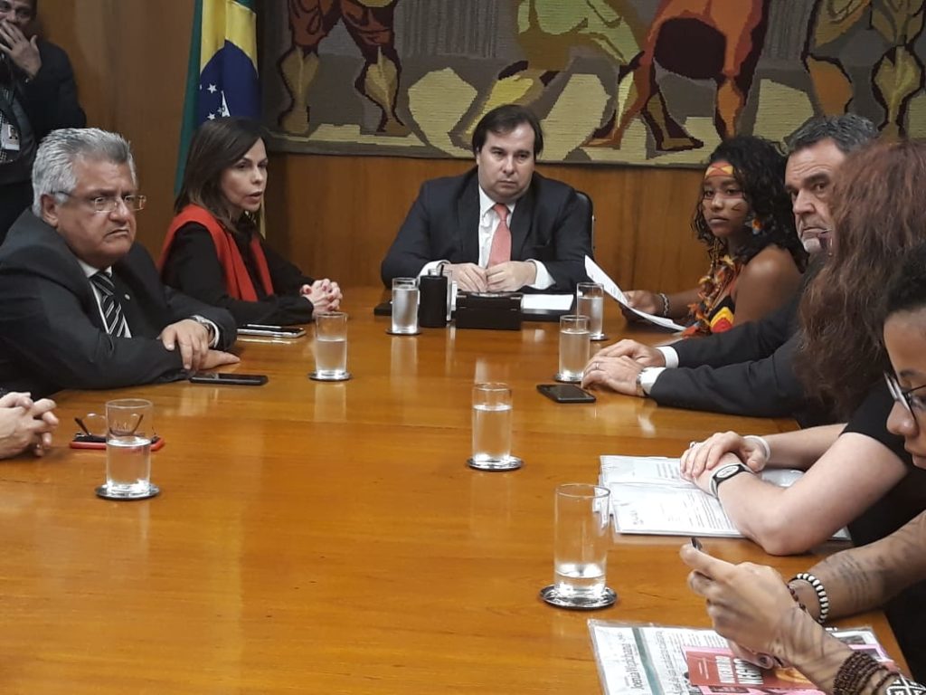 Foto apresenta parlamentares em mesa conversando sobre o FUNDEB. Na foto é possível ver Dorinha Seabra (DEM) e Rodrigo Maia (DEM). Também está presente a Gulmakai Champion Denise Carreira.