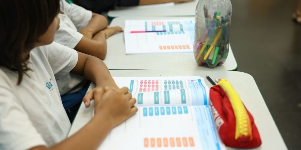 estudantes frente à questionários em uma mesa escolar